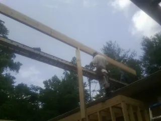 Carpenter setting a ridge beam over a new addition frame — Ice Dam Removal by Roofing Brothers in Gould