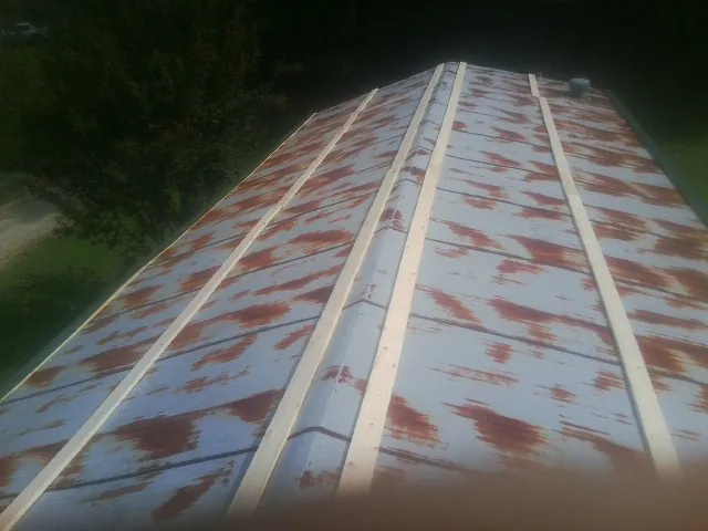 Rusted metal roof panels with new wood purlins before replacement — Storm Damage Roof Repair in Gould by Roofing Brothers
