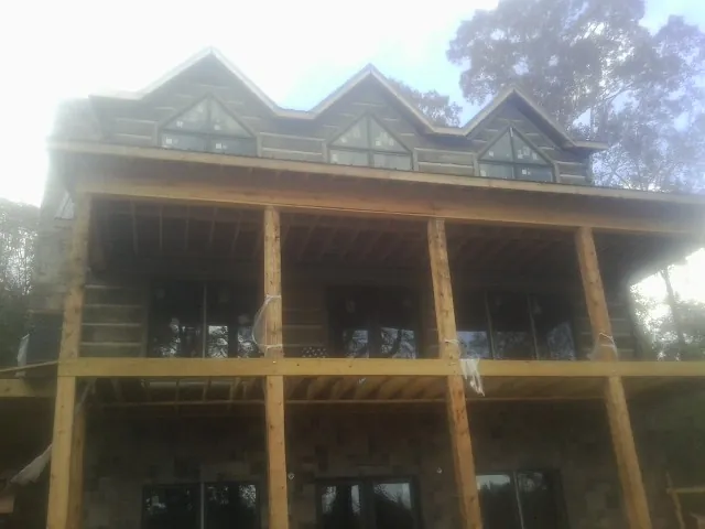 Dormers and porch framing on a large log home under construction — Roof Coating work by our crew in Gould