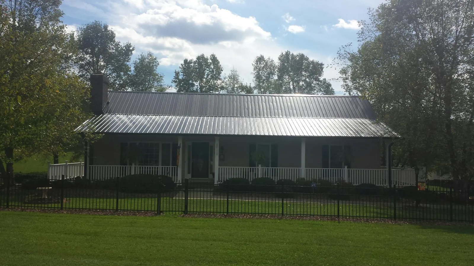 Gray metal roof on a brick ranch with a full width front porch — Gutter Guard Installation work by our crew in Gould