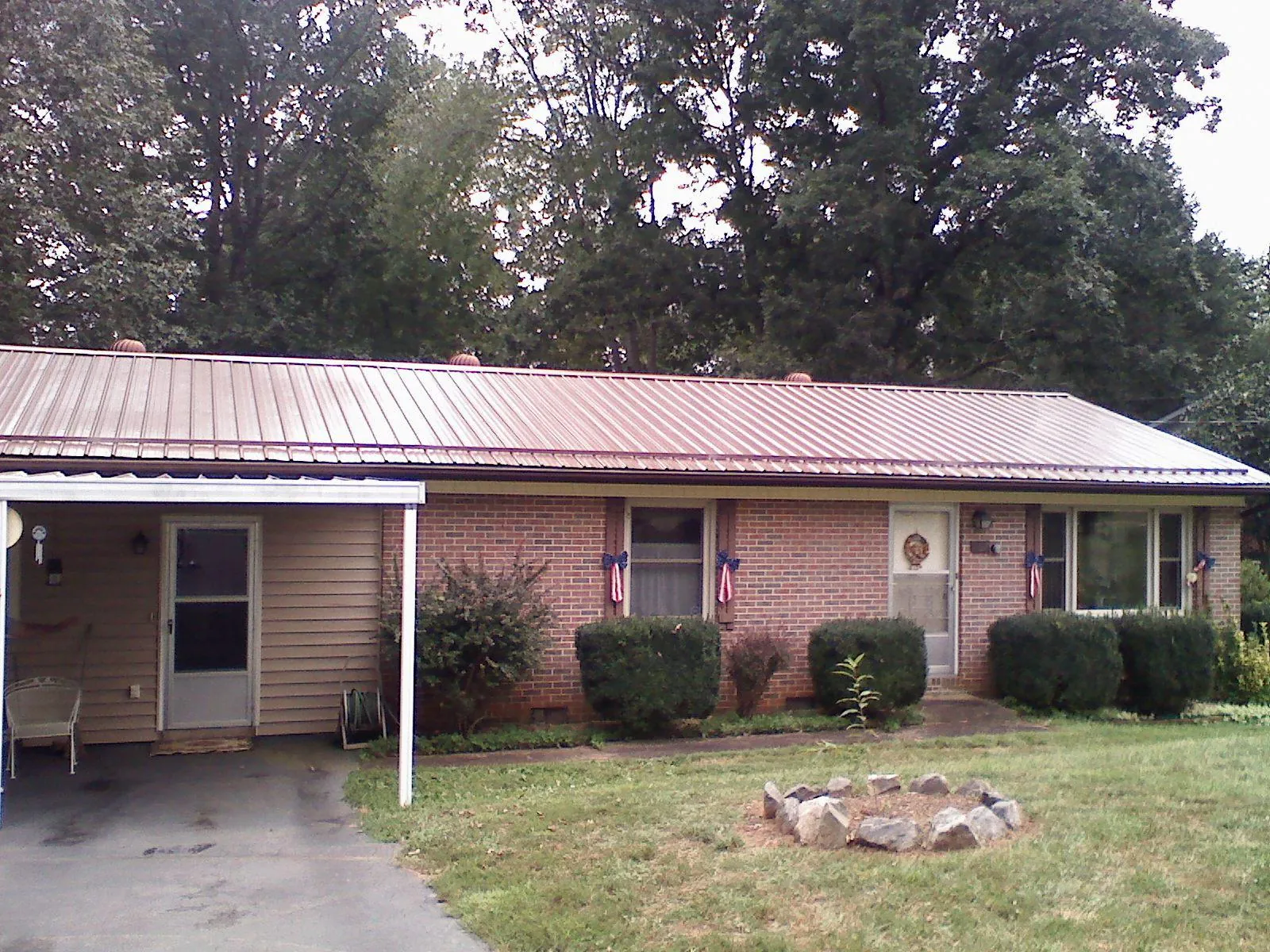 Bronze metal roof and carport on a brick ranch home — Roof Repair work by our crew in Gould