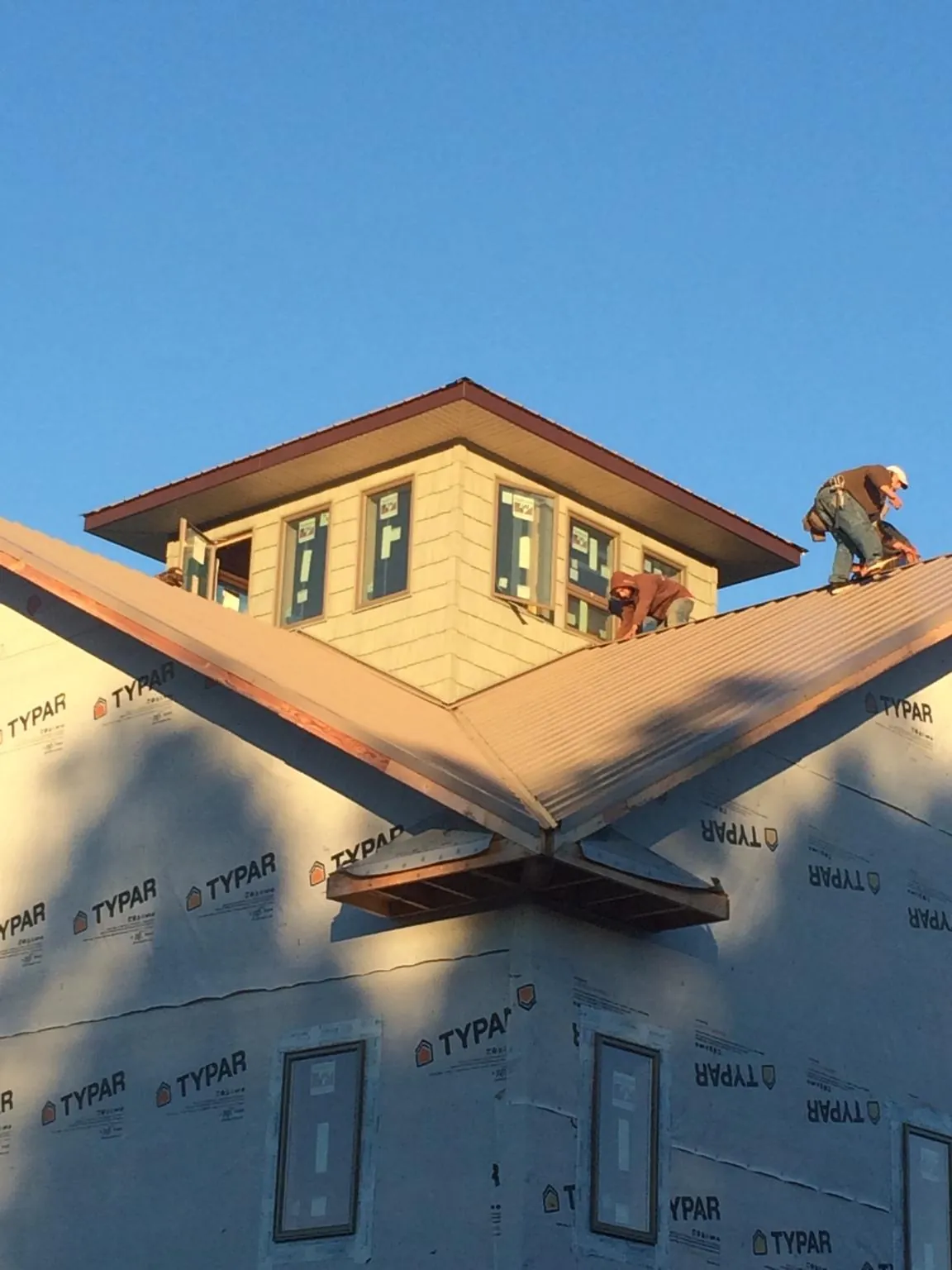 Roofers working around a rooftop cupola on a new metal roof at sunset — Roof Waterproofing in Gould by Roofing Brothers